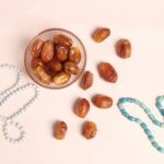 a glass bowl filled with nuts next to a beaded necklace