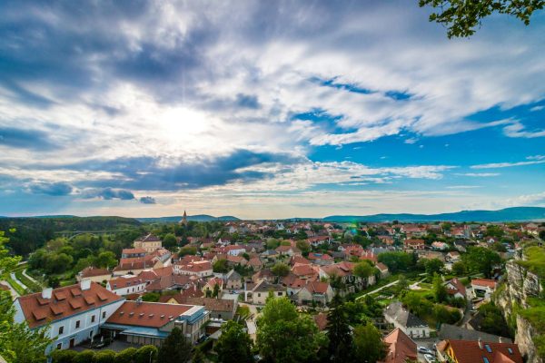 A scenic aerial view of a picturesque village with red-roofed houses under a dramatic sky.