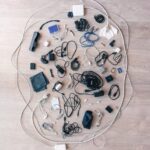 A variety of electronic cables, chargers, and accessories arranged in a flat lay on a wooden floor.