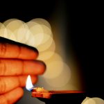 Close-up of a diya flame with bokeh and warm lighting, symbolizing warmth and spirituality.