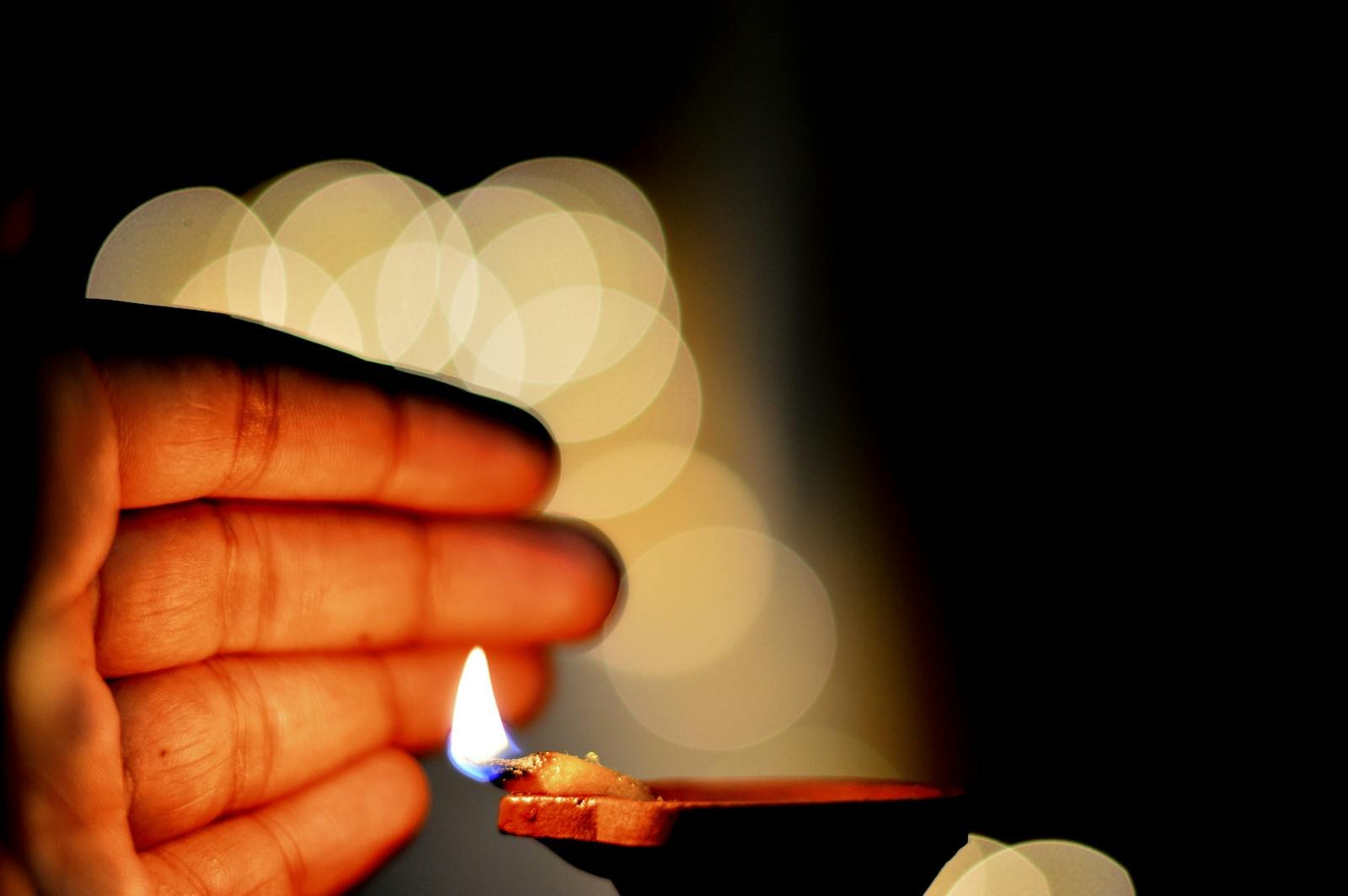 Close-up of a diya flame with bokeh and warm lighting, symbolizing warmth and spirituality.