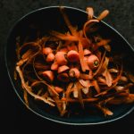 Close-up photo of fresh carrot peels and scraps in a dark bowl, perfect for food waste or preparation themes.