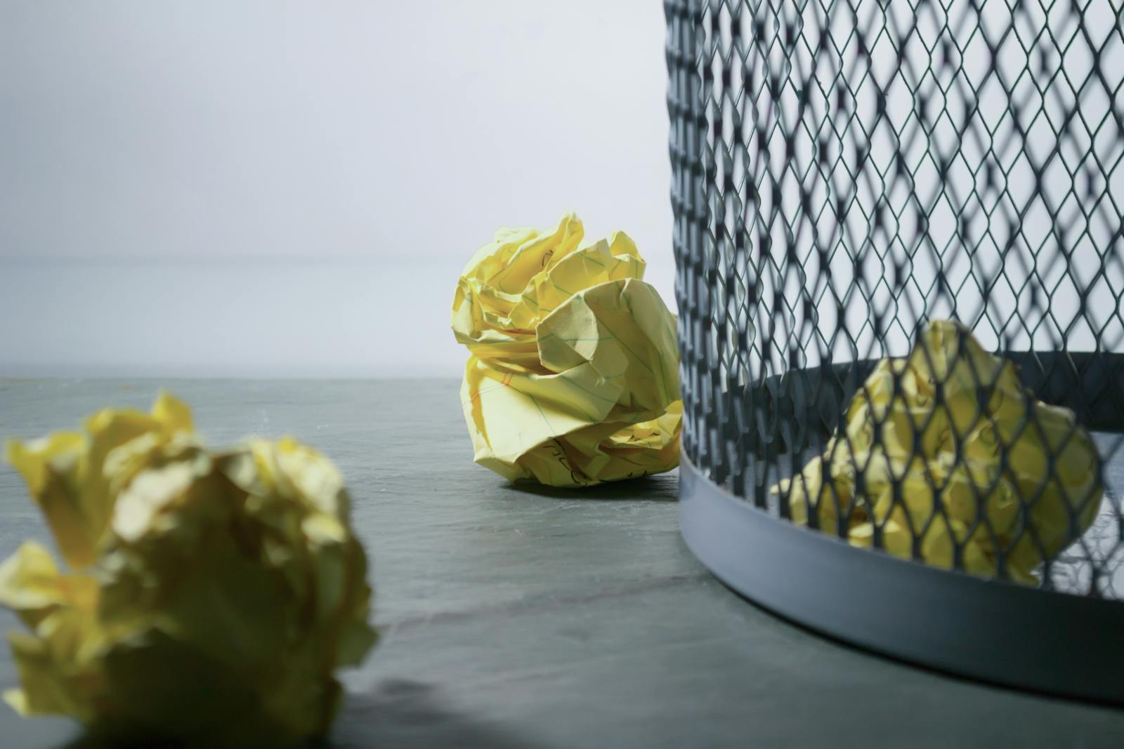 Focus Photo of Yellow Paper Near Trash Can