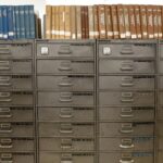Organized filing cabinets stacked with indexed books in a library setting.