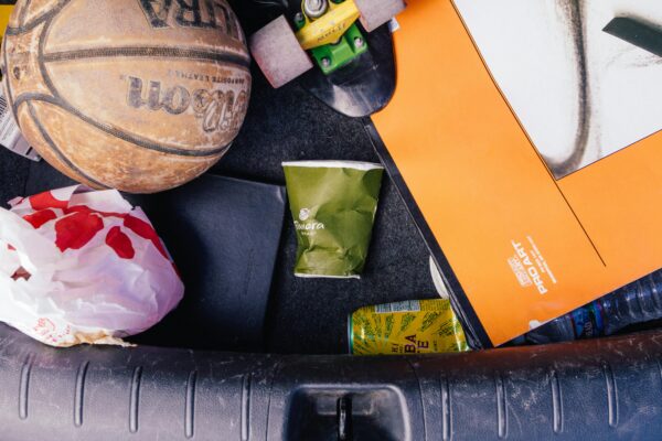 Close-up of basketball, papers, and trash in a car trunk, illustrating untidiness.