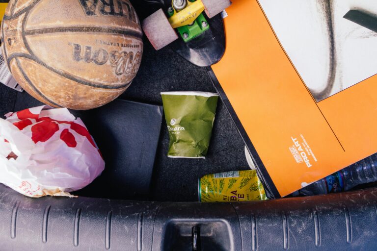 Close-up of basketball, papers, and trash in a car trunk, illustrating untidiness.