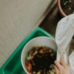 Close-up of a person composting organic waste in a home setting, promoting sustainability.