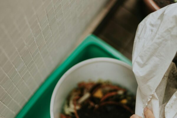 Close-up of a person composting organic waste in a home setting, promoting sustainability.