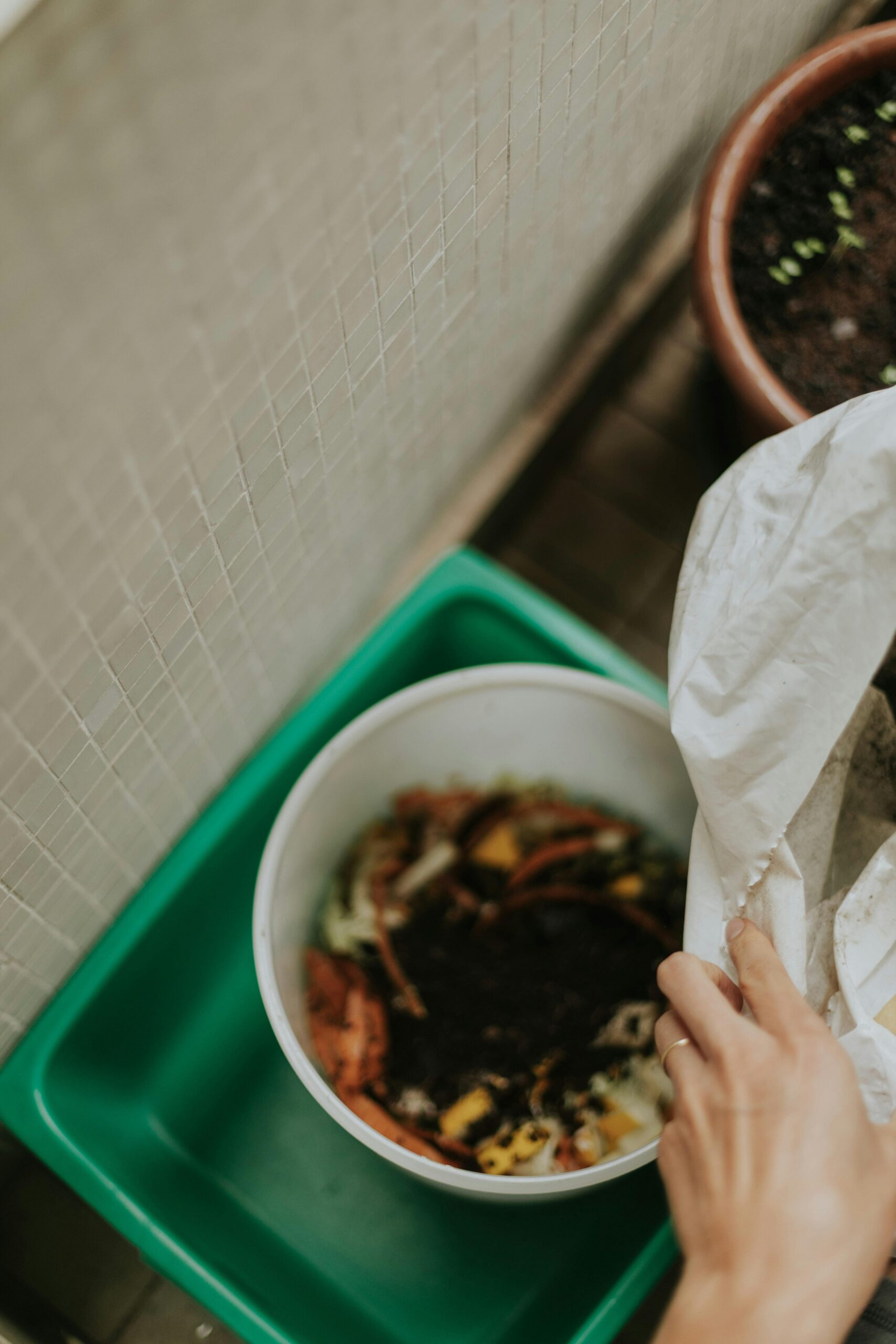 Close-up of a person composting organic waste in a home setting, promoting sustainability.