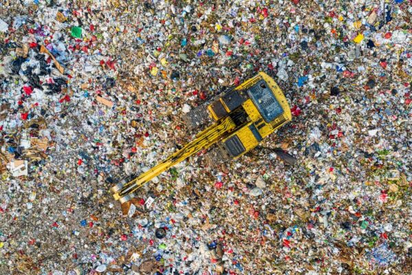 Aerial shot of a landfill with a yellow excavator in South Tangerang, Indonesia.