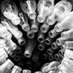 Black and white photo showcasing a spiral arrangement of empty vintage glass bottles.