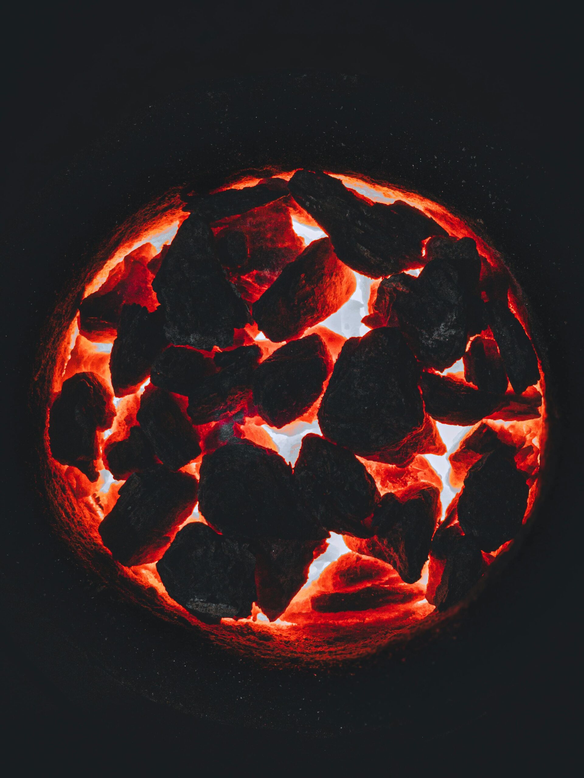 A mesmerizing view of glowing charcoal embers with intense fiery glow and deep contrast.