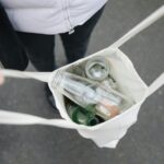Person carrying a tote bag filled with glass bottles for recycling, promoting sustainability.
