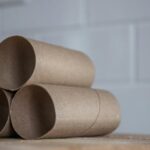 Closeup of stacked brown cardboard tubes of finished toilet paper placed on wooden table
