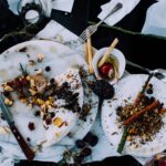 From above of plates with remains of various dishes left after festive dinner on table with cutlery and flowers