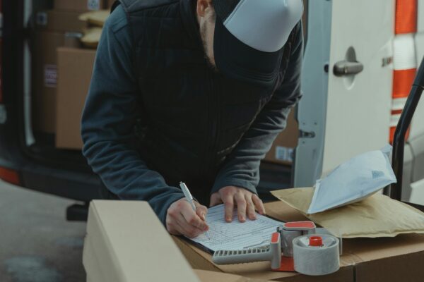 Courier organizing packages from a van, preparing for delivery in a logistics setting.
