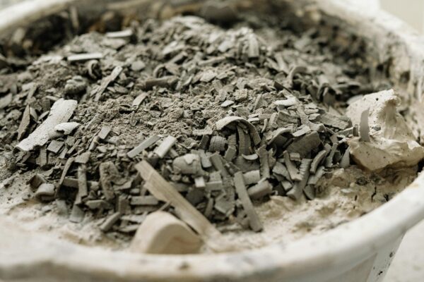 Detailed close-up of a white bowl filled with ashes and debris, highlighting texture.