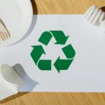 Eco-friendly utensils, light bulb, and recycling symbol on paper emphasize sustainable living.