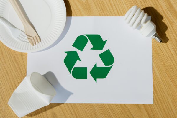 Eco-friendly utensils, light bulb, and recycling symbol on paper emphasize sustainable living.