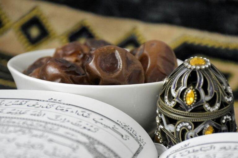 Close-up of a bowl of dates next to an ornate Quran for Ramadan celebrations, featuring intricate patterns.