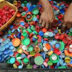 A vibrant assortment of plastic bottle caps being sorted by hand for recycling in Manila.