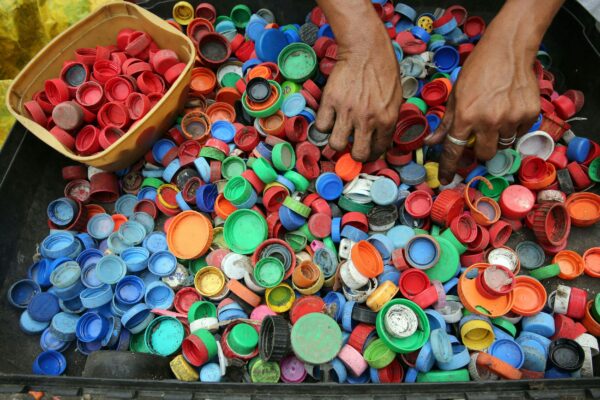 A vibrant assortment of plastic bottle caps being sorted by hand for recycling in Manila.