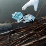 Close-up of a volunteer using gloves to remove waste from a river.