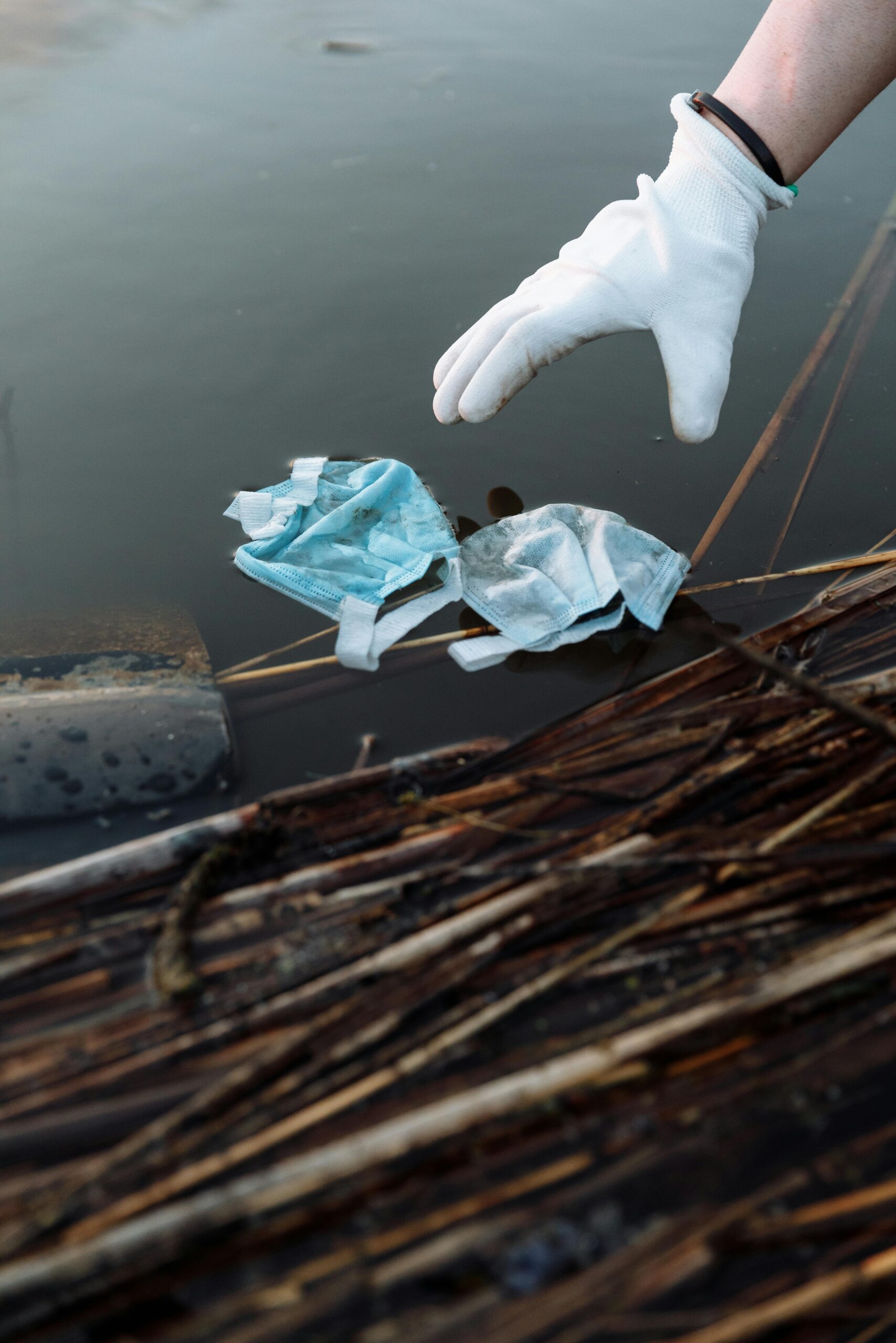 Close-up of a volunteer using gloves to remove waste from a river.