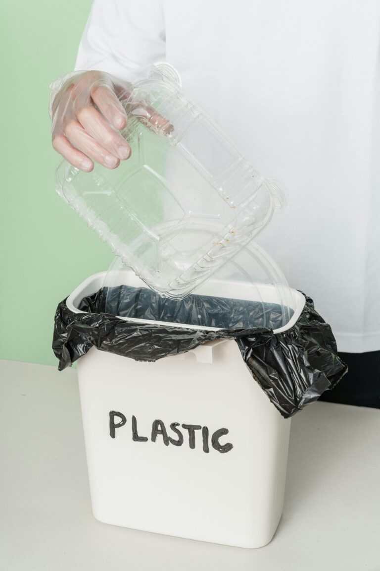 A person disposing of a plastic tray into a recycling bin, promoting eco-friendly habits.