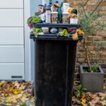 black trash bin with green leaves